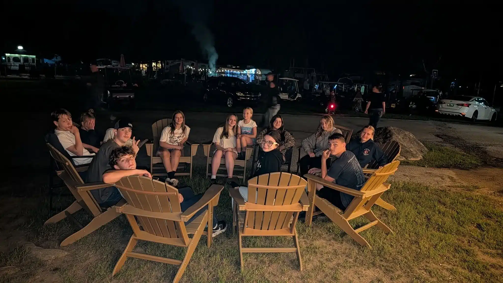 Campers relaxing around a nighttime gathering at Acorn Acres
