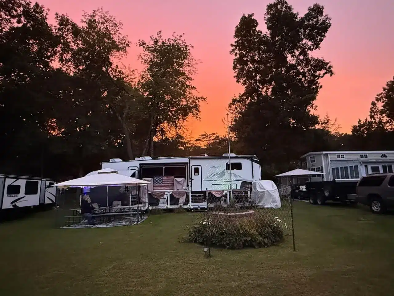Pink and orange sunset above tree-lined RV campsites at Acorn Acres Campground in Bozrah, CT