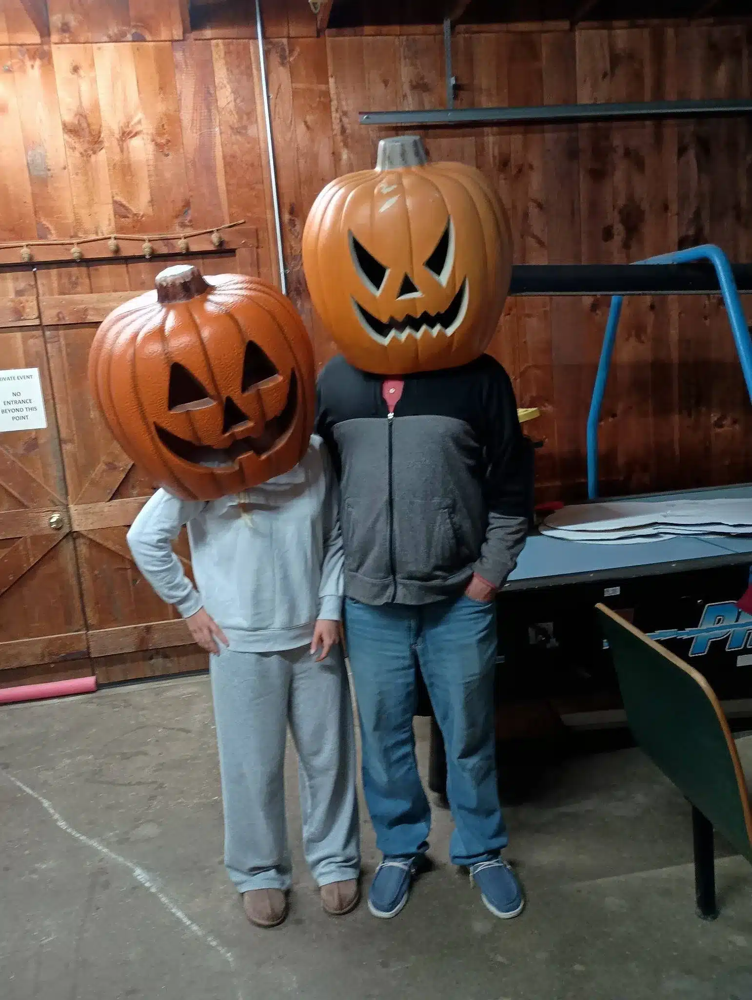 Two people wearing jack-o’-lantern masks inside a wood-paneled room at Acorn Acres Campground in Bozrah, CT