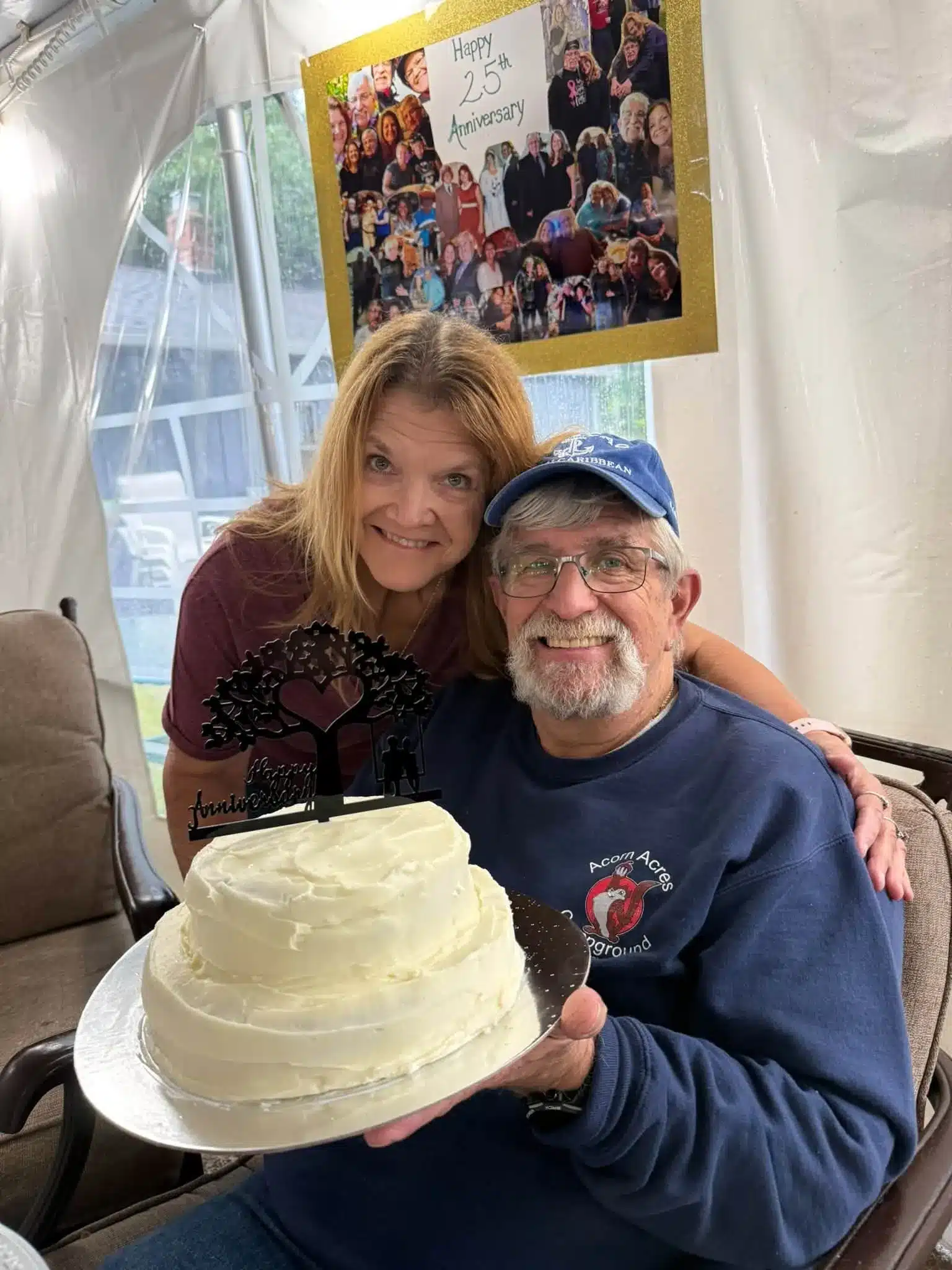 Smiling couple posing together with a cake beside a window inside the event tent at Acorn Acres Campground in Bozrah, CT