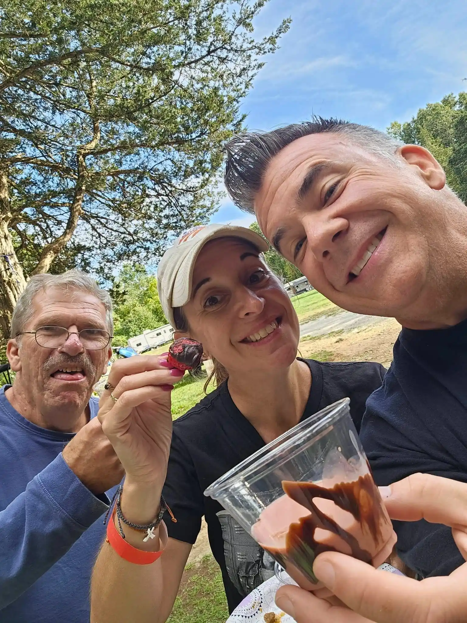 Three smiling campers posing for a selfie outdoors beneath the trees at Acorn Acres Campground in Bozrah, Connecticut