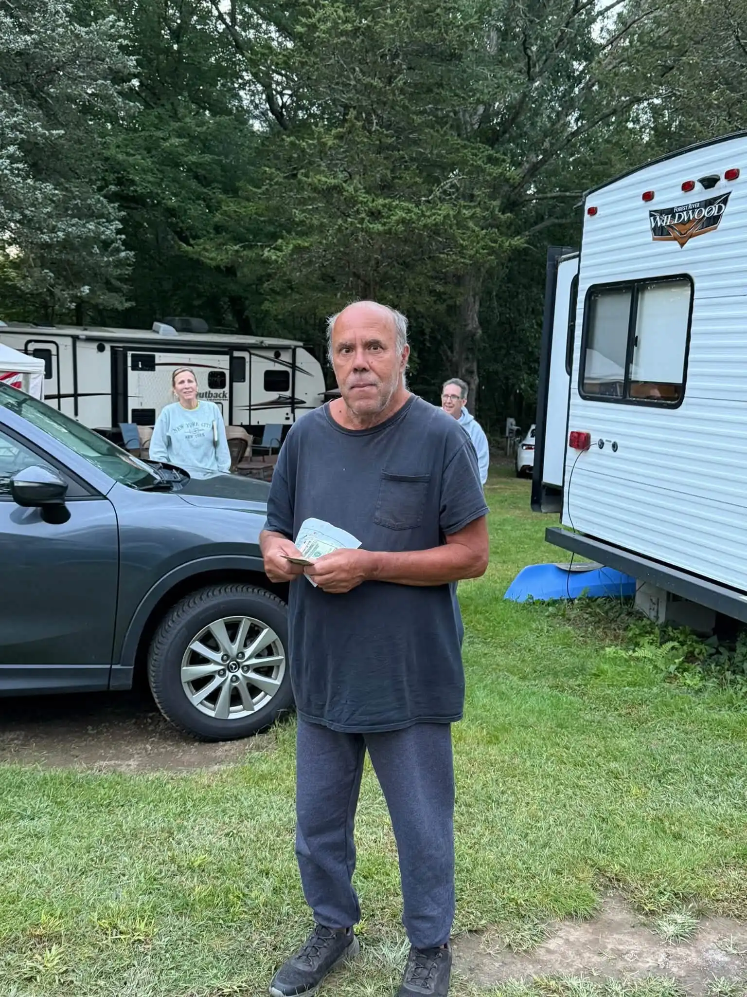 Man standing between a parked vehicle and travel trailer at Acorn Acres Campground in Bozrah, CT