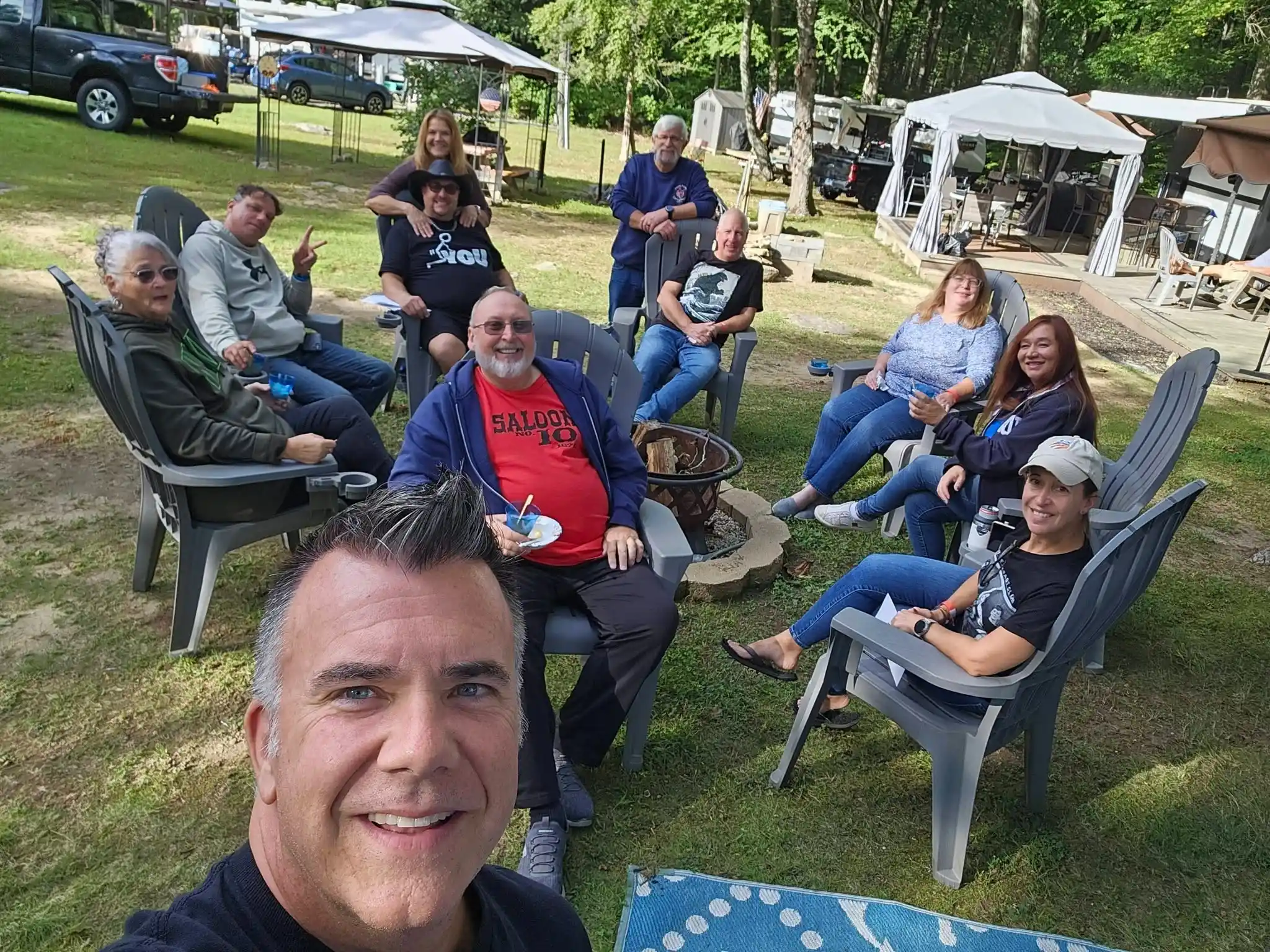 Group of campers relaxing in chairs on a grassy lawn among RV campsites at Acorn Acres Campground, Bozrah CT