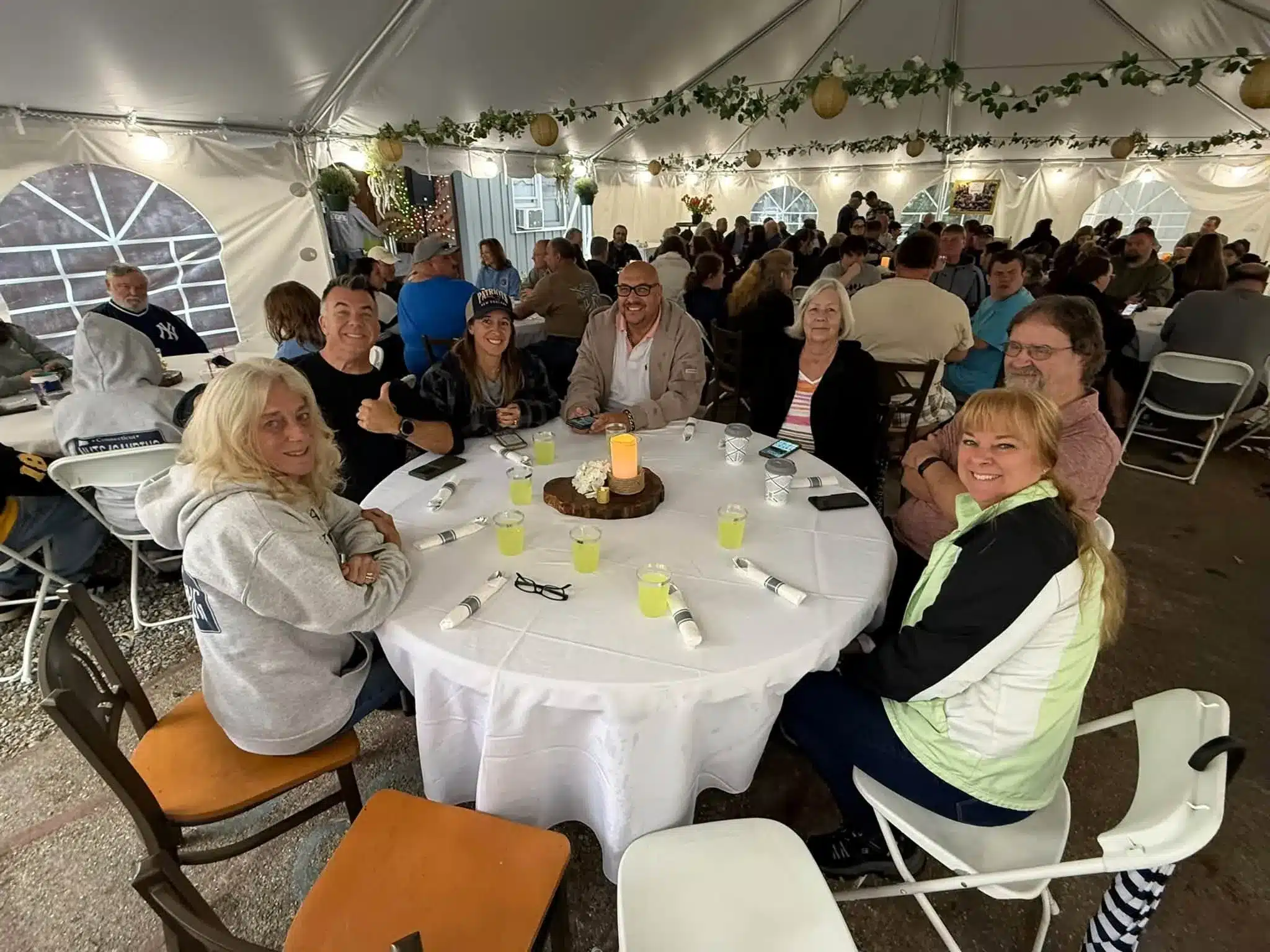 Campers gathered around a dining table beneath string lights at Acorn Acres Campground in Bozrah, CT