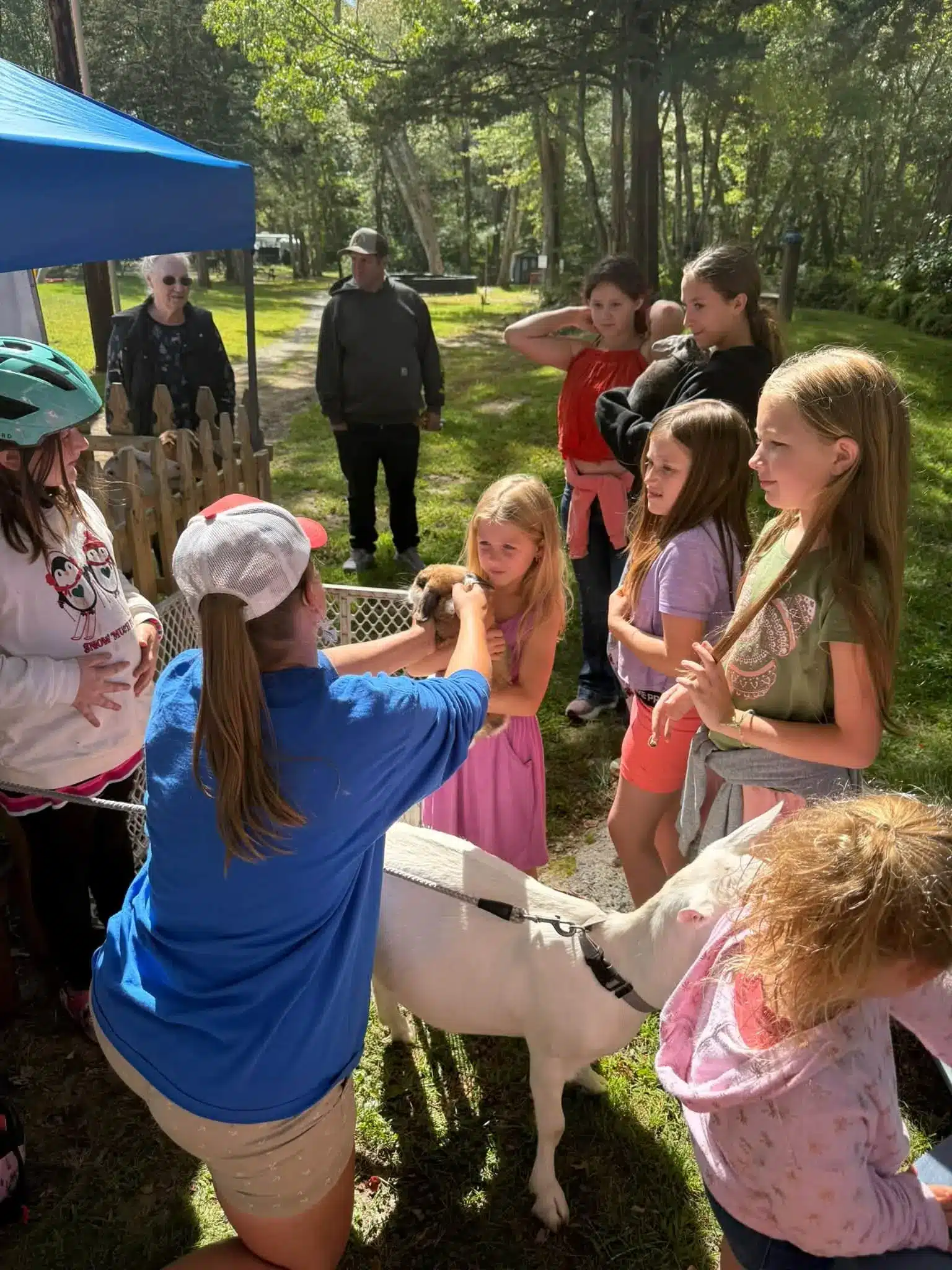 Children and adults gathered on a wooded lawn during an outdoor campground activity at Acorn Acres Campground, Bozrah CT